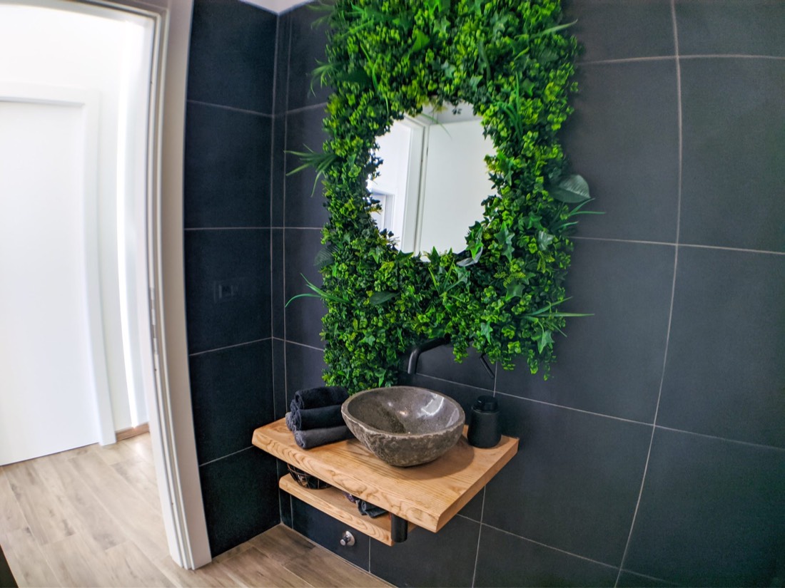 Bagno con lavabo in pietra e specchio con parete verde